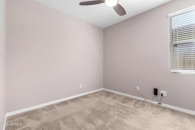 spare room featuring light colored carpet, baseboards, and a ceiling fan