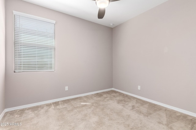 empty room featuring light colored carpet, baseboards, and a ceiling fan