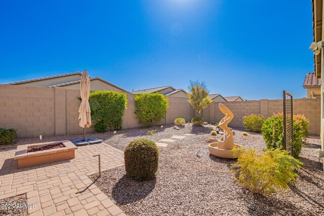 view of yard with a fenced backyard, a fire pit, and a patio area