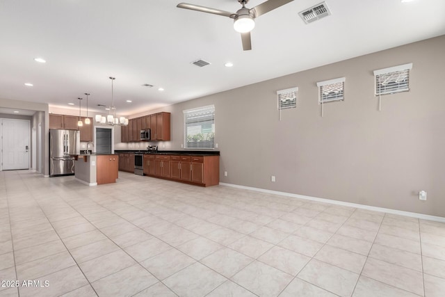 kitchen with visible vents, stainless steel appliances, dark countertops, ceiling fan with notable chandelier, and open floor plan