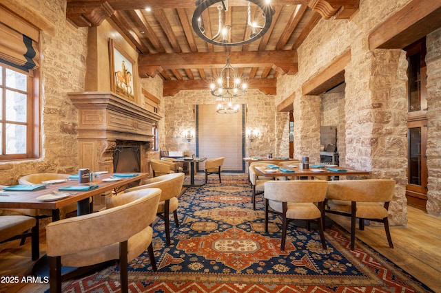 dining room featuring an inviting chandelier, a towering ceiling, wood-type flooring, and beam ceiling