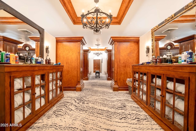 hallway featuring an inviting chandelier, crown molding, and a tray ceiling