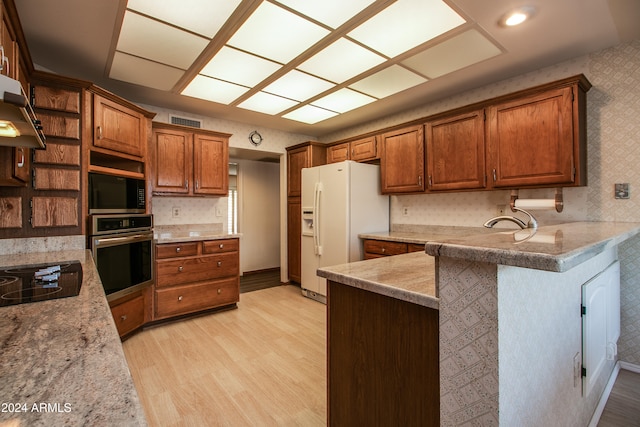 kitchen with kitchen peninsula, light hardwood / wood-style floors, ventilation hood, and appliances with stainless steel finishes