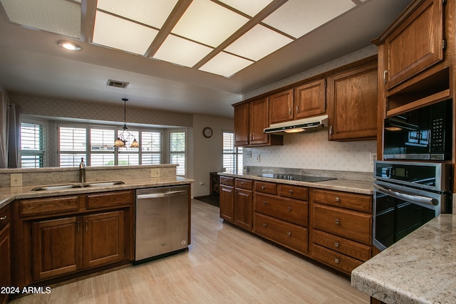 kitchen with light hardwood / wood-style floors, light stone counters, hanging light fixtures, black appliances, and sink