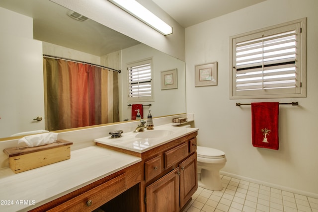 bathroom featuring tile patterned flooring, vanity, a healthy amount of sunlight, and toilet