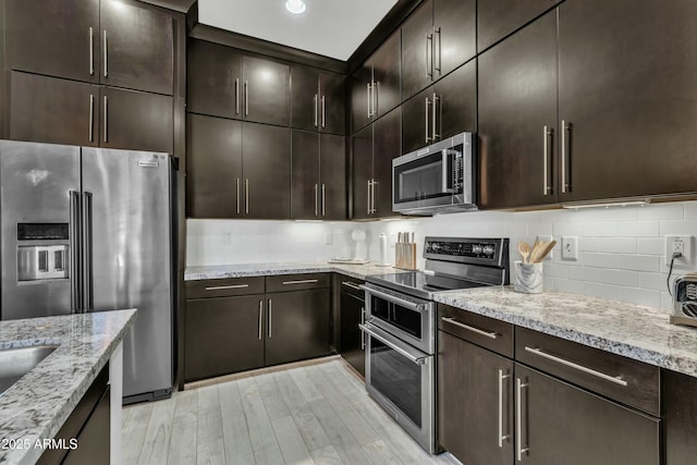 kitchen featuring dark brown cabinets, light stone counters, and appliances with stainless steel finishes