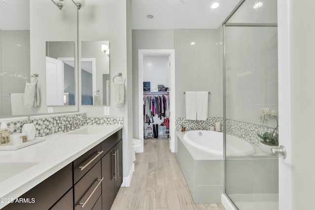 full bathroom featuring decorative backsplash, vanity, hardwood / wood-style flooring, plus walk in shower, and toilet