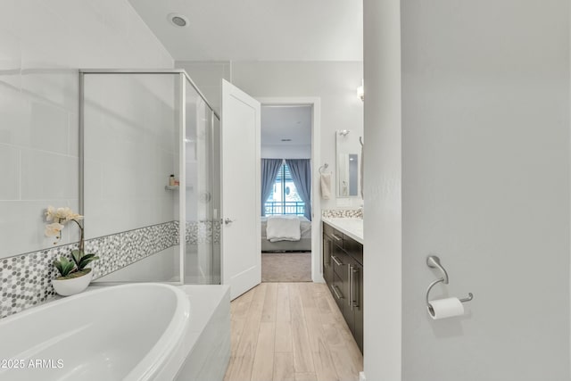 bathroom featuring vanity, plus walk in shower, and wood-type flooring