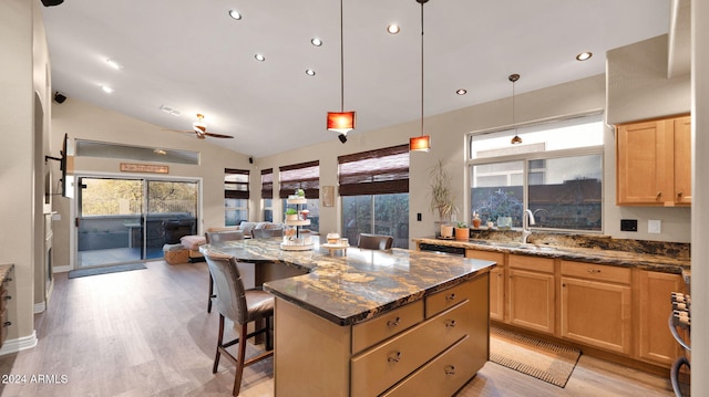 kitchen featuring a kitchen bar, ceiling fan, dark stone countertops, a center island, and lofted ceiling