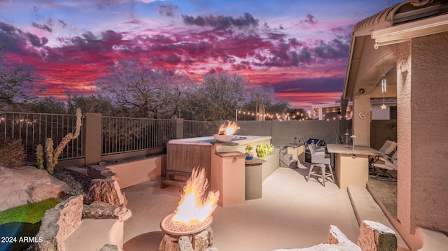 patio terrace at dusk with a bar and an outdoor kitchen