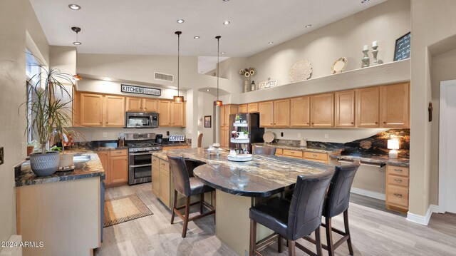 kitchen with a center island, stainless steel appliances, hanging light fixtures, and a breakfast bar area