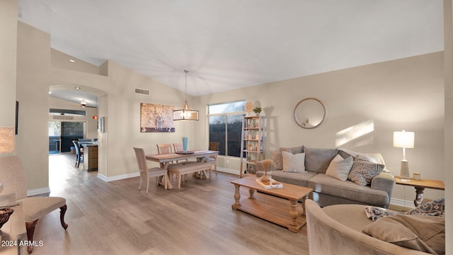 living room with a notable chandelier, wood-type flooring, and vaulted ceiling