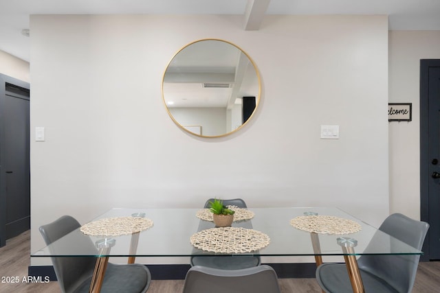 dining space featuring wood finished floors and beam ceiling