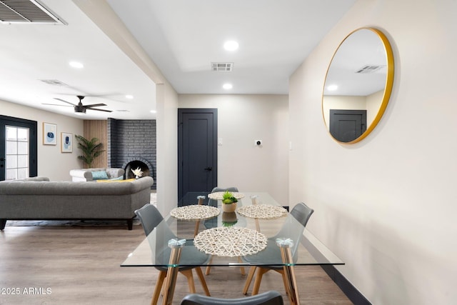 dining space with recessed lighting, light wood-style flooring, ceiling fan, baseboards, and a fireplace