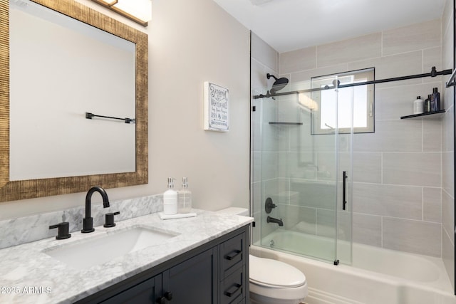 bathroom with toilet, bath / shower combo with glass door, and vanity