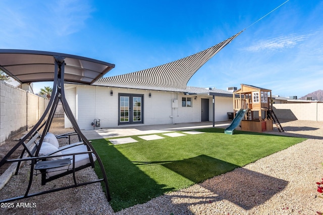 rear view of house with a playground, french doors, and a patio