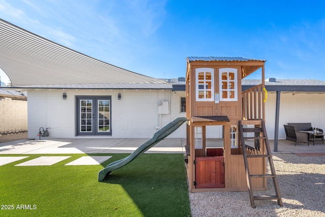 rear view of property with a patio area, fence, french doors, and a playground