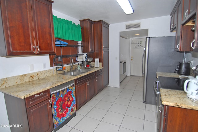 kitchen with light stone counters, sink, light tile patterned floors, and stainless steel appliances