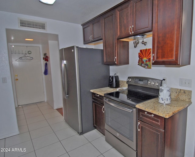 kitchen with light stone countertops, light tile patterned floors, and stainless steel appliances