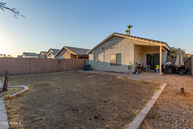 back house at dusk with a patio and cooling unit