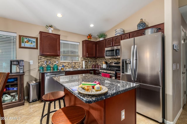 kitchen with a center island, sink, vaulted ceiling, stainless steel appliances, and backsplash