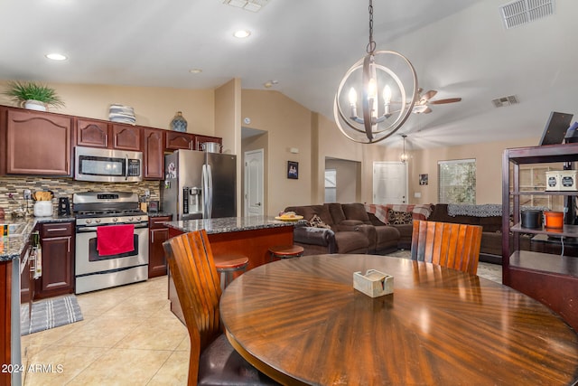 tiled dining area with ceiling fan with notable chandelier and lofted ceiling