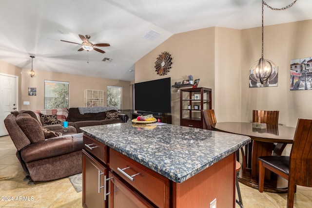 kitchen with hanging light fixtures, light tile patterned flooring, ceiling fan with notable chandelier, a kitchen island, and lofted ceiling