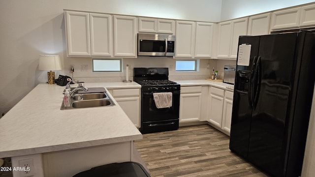 kitchen with light hardwood / wood-style floors, sink, black appliances, and kitchen peninsula