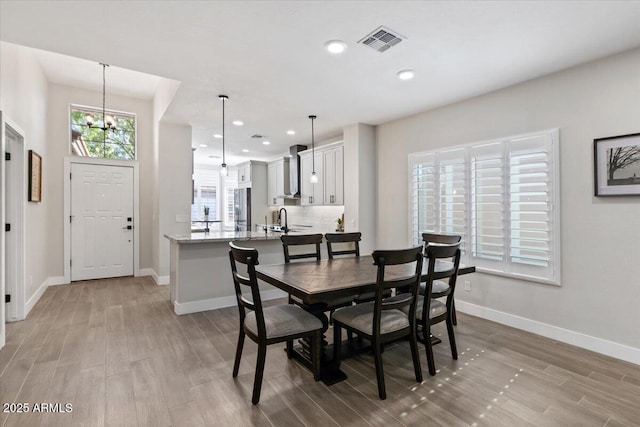 dining area with sink, a notable chandelier, and light hardwood / wood-style flooring