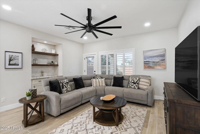 living room with light hardwood / wood-style flooring, ceiling fan, and bar area