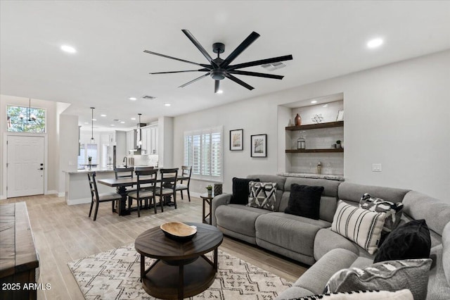 living room featuring plenty of natural light, ceiling fan, and light hardwood / wood-style flooring