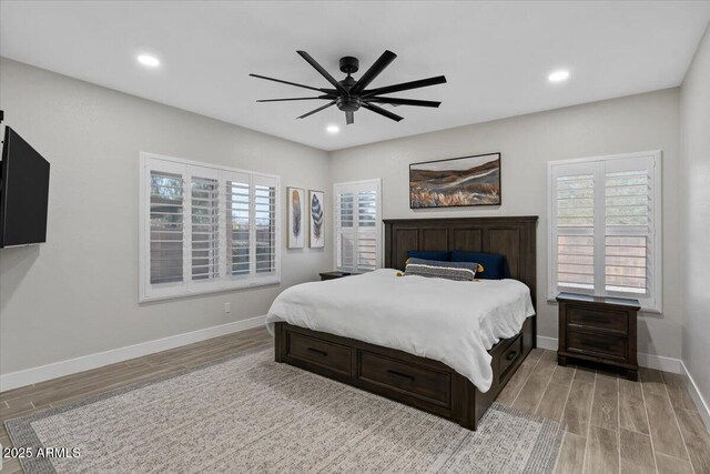 bedroom featuring hardwood / wood-style flooring, ceiling fan, and multiple windows