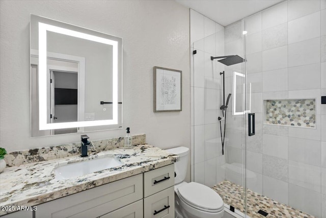 bathroom with vanity, a shower with door, and toilet