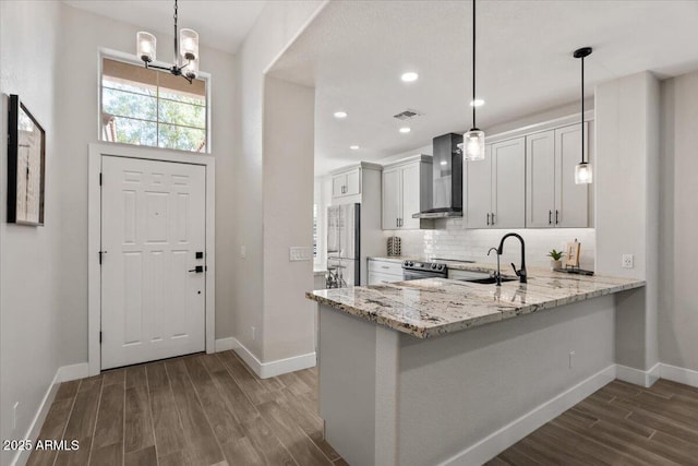 kitchen featuring pendant lighting, sink, white cabinets, kitchen peninsula, and wall chimney exhaust hood