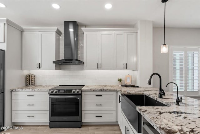 kitchen with pendant lighting, tasteful backsplash, white cabinets, stainless steel range with electric cooktop, and wall chimney range hood