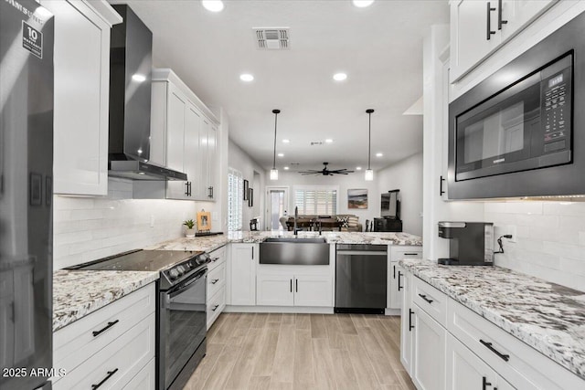 kitchen featuring sink, white cabinetry, black range with electric stovetop, built in microwave, and wall chimney exhaust hood