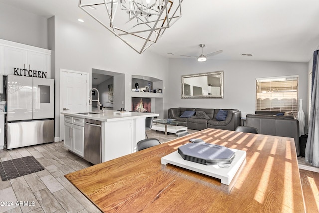 kitchen featuring sink, an island with sink, a breakfast bar area, white cabinets, and appliances with stainless steel finishes