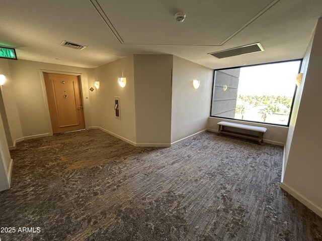 unfurnished room with baseboards, attic access, wood finished floors, and visible vents