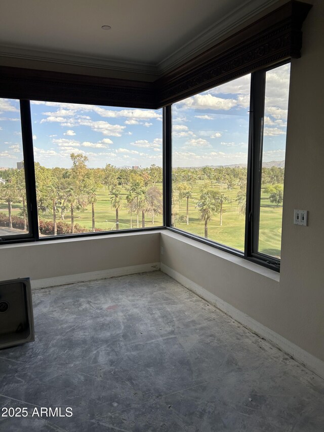 unfurnished room featuring crown molding, baseboards, a wealth of natural light, and unfinished concrete flooring