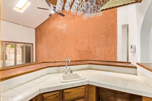 4922 W Fallen Leaf Ln, Glendale, AZ 85310 - kitchen with a sink, tile counters, high vaulted ceiling, a skylight, and ceiling fan