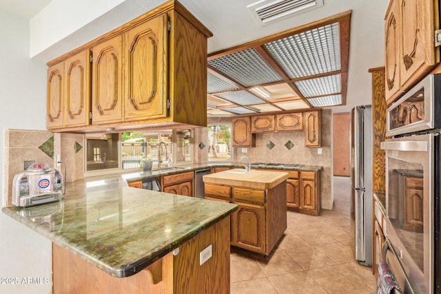 4922 W Fallen Leaf Ln, Glendale, AZ 85310 - kitchen featuring a peninsula, stainless steel appliances, a sink, and an island with sink