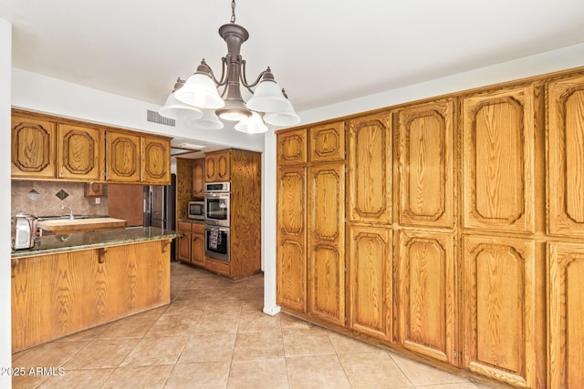4922 W Fallen Leaf Ln, Glendale, AZ 85310 - kitchen featuring brown cabinets, stainless steel appliances, a chandelier, and light tile patterned floors