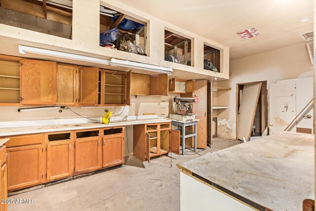 4922 W Fallen Leaf Ln, Glendale, AZ 85310 - kitchen with open shelves, unfinished concrete flooring, brown cabinetry, and light countertops