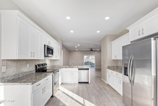 kitchen featuring kitchen peninsula, white cabinetry, light stone countertops, and stainless steel appliances