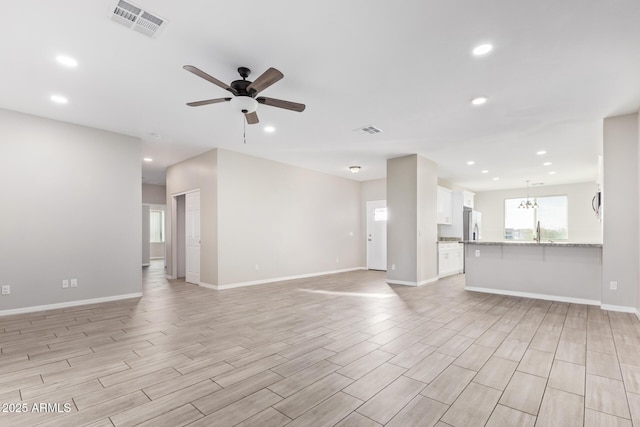 unfurnished living room with ceiling fan with notable chandelier