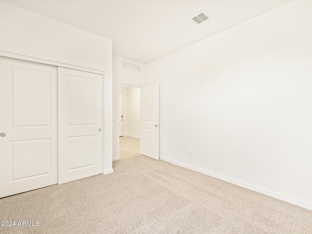 unfurnished bedroom with light carpet and a closet