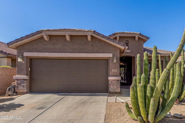 view of front of house featuring a tile roof, stucco siding, concrete driveway, a garage, and stone siding