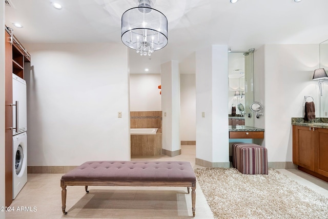 sitting room with stacked washing maching and dryer and a chandelier