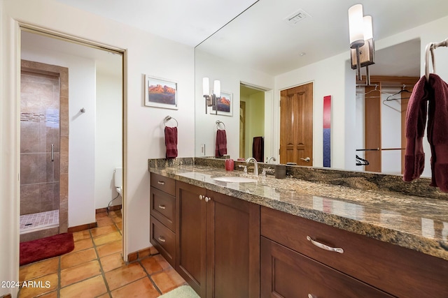 bathroom with tiled shower, vanity, and toilet