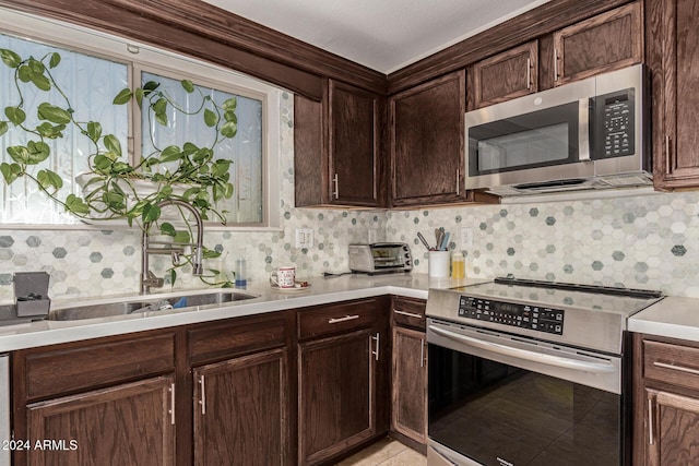 kitchen with dark brown cabinets, stainless steel appliances, tasteful backsplash, and sink